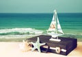 Vintage case with old boat toy and starfish in front of seascape. travel concept. filtered image.