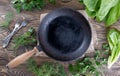 Vintage cast iron skillet on rustic wood background with herbs. Royalty Free Stock Photo