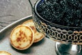 Vintage caviar dish with black caviar and blinis, a closeup on black