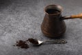 Vintage cezve with coffee and a spoon with ground coffee on grey background