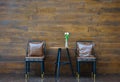 Vintage chairs with dark brown leather seat decorated for wait guests, near the wooden wall