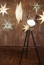 Vintage chrome tripod spotlight and stars ligths on brown wood wall, copy space. Floor lamp, lampshade. Christmas background