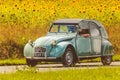 Vintage Citroen 2CV in front of a field with blooming sunflowers