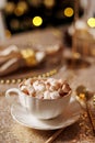 Vintage classic white porzellan cup with saucer with cacao and marshmallow on golden glittering tablecloth. Christmas or