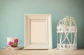 Vintage classical white frame on wooden table with porcelain cup and lantern