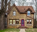 Vintage clinkerbrick two story home with arched red door and flowers in front window and copper gutters and drain pipes in winder Royalty Free Stock Photo