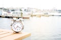 Vintage clock silver put on wood near port with background boat, sea and white sky in morning time, clock concept in holiday time Royalty Free Stock Photo