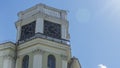 The vintage clock tower on facade of the residential building on blue sky background with sun glare. Urban backgrouund. Royalty Free Stock Photo