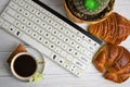 Stilllife of coffee cup with espresso, croissant, biscuit, flower and imitation of keyboard on a wooden background Royalty Free Stock Photo