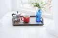 Coffee mug, coffee maker with vase of flowers on wooden tray on windowsill Royalty Free Stock Photo