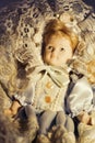 Vintage collectible porcelain doll wearing period clothing with blond hair and headdress and dreamy look Royalty Free Stock Photo