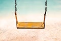 Vintage color tone style of yellow swing on sand sea beach summer day