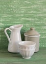 Vintage cookware - enameled jar, pitcher and white ceramic bowl on a green wooden surface Royalty Free Stock Photo