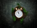 Vintage copper Alarm Clock Five Minutes to Midnight New Years Countdown Christmas Wreath Fir Tree Branches on Black Background