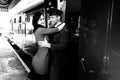 Vintage couple embracing and laughing on railway station platform as train arrives Royalty Free Stock Photo