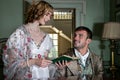 Vintage couple in period costume sitting around piano playing tunes and singing songs