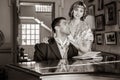 Vintage couple in period costume sitting around piano playing tunes and singing songs