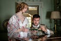 Vintage couple in period costume sitting around piano playing tunes and singing songs