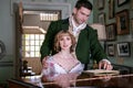 Vintage couple in period costume sitting around piano playing tunes and singing songs