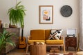 Vintage and cozy space of dining room with mock up poster frame, yellow sofa, wooden coffee table, guitar, plants, commode,