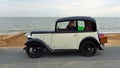 Vintage Cream and Black Austin Seven Motor Car with basket Parked on Seafront Promenade beach and sea in background.