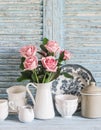 Vintage crockery in english style and rose bouquet on blue wooden rustic background. Kitchen still life in vintage country style. Royalty Free Stock Photo