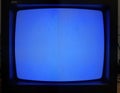 Vintage CRT TV with blue screen. Static noise indicates no signal. Retro tech display isolated against black background.