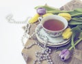 cup of tea with lilac and yellow tulips, craft paper and silver beads