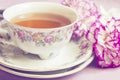 Vintage cup of tea with pink blooming carnation, retro background