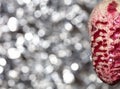 Vintage decorative christmas bauble in a shape of a pine cone in a pink color against a silver blurry bokeh star background Royalty Free Stock Photo