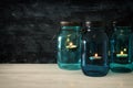 vintage decorative magical mason jars with candle light on wooden table Royalty Free Stock Photo