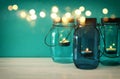 vintage decorative magical mason jars with candle light on wooden table Royalty Free Stock Photo