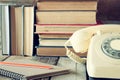 Vintage dial phone, phone book next to stack of old books over wooden table. vintage filtered image Royalty Free Stock Photo