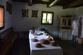 Vintage dining-room with long table and hitorically dressed female figure in right corner