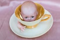 Vintage doll head inside antique coffee or tea cup with saucer - creepy and surreal. Royalty Free Stock Photo