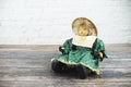 Vintage doll wearing with green dress sit on wooden floor over on white brick wall background Royalty Free Stock Photo