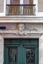 Head sculpture and relief stone elements above top of old green painted wooden door. Antique ornate metal gratings of vintage door Royalty Free Stock Photo