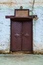 A vintage door in an old farmhouse or barn, a rusty signboard with an empty space for text and lantern, wall painted with white