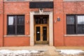 Vintage doorway with wooden doors attached to old red brick industrial building