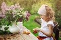 Vintage dressed child girl decorating cakes with flowers on garden tea party in spring