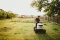 Vintage effect of landscaping works. Male worker riding a tractor grass trimmer