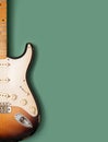 Vintage electric guitar against pastel green background.