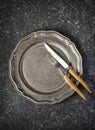 Vintage empty plate and fork and knife on dark grey stone background Royalty Free Stock Photo