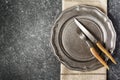 Vintage empty plate and fork and knife with napkin on dark grey stone background Royalty Free Stock Photo