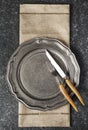 Vintage empty plate and fork and knife with napkin on dark grey stone background Royalty Free Stock Photo