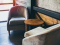 Vintage fabric armchair with round wooden table near the wall, concrete, black steel and wooden wall Royalty Free Stock Photo