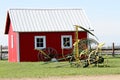 Vintage farm equipment in front of red building. Royalty Free Stock Photo