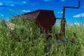 Vintage farming disc harrow in a field surrounded by tall grass