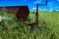 Vintage farming disc harrow in a field surrounded by tall grass with wind turbines