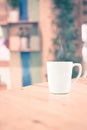 Vintage filter : White coffee cup on wood table at blur cafe background with bokeh light. Royalty Free Stock Photo